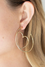 Load image into Gallery viewer, Glistening gold wire delicately bends into an airy heart frame inside a classic gold hoop, creating a flirtatious display. Earring attaches to a standard post fitting. Hoop measures approximately 2" in diameter. Sold as one pair of hoop earrings.