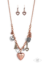Load image into Gallery viewer, An array of brass, copper, and silver heart charms trickle from a section of bold copper chain, creating a whimsical fringe below the collar. The largest heart charm is inscribed with the phrase, “With all my heart” on one side and a short bible verse on the other that reads, "Love the lord thy God with all your heart. Luke 10:27.” Features an adjustable clasp closure. Sold as one individual necklace. Includes one pair of matching earrings.