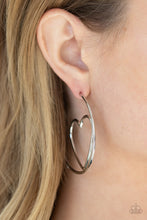 Load image into Gallery viewer, Glistening silver wire delicately bends into an airy heart frame inside a classic silver hoop, creating a flirtatious display. Earring attaches to a standard post fitting. Hoop measures approximately 2" in diameter. Sold as one pair of hoop earrings.