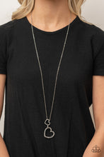 Load image into Gallery viewer, A silver heart engraved with the word "Grandma," dangles from two smaller hearts at the bottom of a lengthened silver chain. The first heart is accented with sparkly white rhinestones creating an affectionately sentimental pendant. Features an adjustable clasp closure. Sold as one individual necklace. Includes one pair of matching earrings.