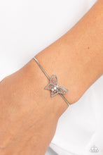 Load image into Gallery viewer, A deceptively simple silver butterfly charm glides along a silver snake chain for a whimsical flair along the wrist. Dainty, iridescent rhinestones encrust along the butterfly's body, creating an understated shimmer, while intricate, airy wings fold out from the sparkle, adding a 3D effect to the design. Features an adjustable sliding knot closure. Due to its prismatic palette, color may vary. Sold as one individual bracelet.