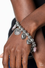 Load image into Gallery viewer, Decorative silver filigree, silver-studded, and pink gem heart charms swing from a collection of shiny silver beads, and silver beads with a dot motif. Threaded along an elastic stretchy band, the charming bracelet creates a timeless romantic centerpiece around the wrist. Sold as one individual bracelet.