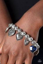 Load image into Gallery viewer, Decorative silver filigree, silver-studded, and blue gem heart charms swing from a collection of shiny silver beads, and silver beads with a dot motif. Threaded along an elastic stretchy band, the charming bracelet creates a timeless romantic centerpiece around the wrist. Sold as one individual bracelet.