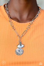 Load image into Gallery viewer, A harmonious compilation of charms, featuring tranquil shades of blue and accents of black, gather at the bottom of a handcrafted chain. Elongated paperclip links and oversized jump rings interlock as they fall down the neckline, leading to the boisterous collection of charms, which include a rectangular silver plate stamped with the phrase, good vibes, a warped silver disc embossed in a sunburst pattern, and an eye with exaggerated eyelashes. Includes one pair of matching earrings.