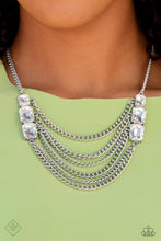 Load image into Gallery viewer, Layers of thick, silver curb chain drape across the chest, creating a fierce, industrial statement piece. Three blinding white, emerald-cut gems that gradually increase in size, are affixed to each side of the swooping chains, adding dramatic sparkle to the collision of grit and glitz. Features an adjustable clasp closure. Includes one pair of matching earrings.