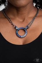Load image into Gallery viewer, A collision of mismatched gunmetal chains gives way to a studded gunmetal pendant that has been encrusted in glittery blue UV rhinestones. The result is a gritty, industrial design with endless attitude. Features an adjustable clasp closure. Sold as one individual necklace. Includes one pair of matching earrings.