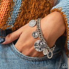 Load image into Gallery viewer, A collection of refined charms add some texture and shimmer to this monochromatic mash-up. An oversized, hammered disc is stamped with the phrase "be still" with the scripture reference "Psalm 48:10" listed underneath it. A smaller, hammered disc with a sprinkle of white rhinestones in its center and a silver disc featuring a scalloped ring in its center glide next to the oversized silver disc. A silver ring with serrated texture, and a silver disc with hammering and ring of white rhinestones glimmers.