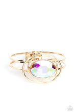 Load image into Gallery viewer, Featured in the center of airy, shiny gold bands, an oversized, faceted iridescent oval gem rests atop the wrist for a dazzling pop of color. Warped, shiny gold rings seemingly float around the sparkly gem for a whimsical finish. Features a hinged closure. Due to its prismatic palette, color may vary. Sold as one individual bracelet.