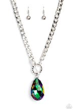 Load image into Gallery viewer, Featuring an elegant lariat closure, an oversized, faceted, stellar UV shimmery teardrop gem, encased in an elevated pronged silver frame cascades from the bottom of a silver curb chain in a whimsical fashion. Dainty hematite rhinestones are encrusted along the ring as the lariat closure loops through for a touch of edgy shimmer to the exaggerated sparkly design. Due to its prismatic palette, color may vary. Sold as one individual necklace. Includes one pair of matching earrings.