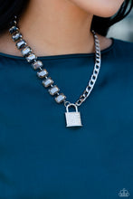 Load image into Gallery viewer, Infused on a classic silver chain, a strand of thick silver curb chain, and a collection of exaggerated, smoky radiant-cut gems in silver pronged fittings combine to create a collision of industrial color around the neckline. An oversized silver lock charm, embossed in white rhinestones, dangles from the gritty display for a touch of soft glitz to the design. Features an adjustable clasp closure. Sold as one individual necklace. Includes one pair of matching earrings.