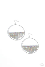 Load image into Gallery viewer, A curtain of iridescent rhinestones is stretched between the edges of a skinny, oversized silver hoop, creating a shimmering display. The rhinestones taper towards the center as they sway and cascade, adding sparkly movement for a fierce industrial finish. Earring attaches to a standard fishhook fitting. Due to its prismatic palette, color may vary. Sold as one pair of earrings.