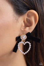 Load image into Gallery viewer, A solitaire white pearl, pressed in a white rhinestone-encrusted gold hoop, gleams atop a pearl-dotted heart frame resulting in a dazzling statement piece. A black velvet ribbon fans out from the pearly centerpiece further infusing the design with elegance. Earring attaches to a standard post fitting. Sold as one pair of post earrings.