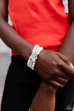 Load image into Gallery viewer, Strung along elastic stretchy bands, three strands of high-sheen classic white pearls wrap around the wrist. Featured atop the pearly collection, a loopy silver bow, filled with glistening white rhinestones is attached to the center of the wrist for a dramatically dazzling finish. Sold as one individual bracelet.