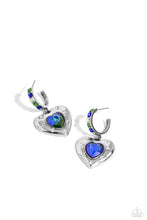 Load image into Gallery viewer, Featuring a UV shimmer, a green/blue heart gem is pressed into an antiqued silver heart frame adorned in white rhinestones. The antiqued heart sways from the bottom of a thick silver hoop encrusted in square green, blue, and white gems resulting in a whimsical fashion. Earring attaches to a standard post fitting. Hoop measures approximately 3/4" in diameter. Due to its prismatic palette, color may vary. Sold as one pair of hoop earrings.
