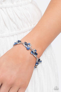 An eclectic collection of white and blue round rhinestones in varying sizes and marquise-cut gems in a blue shade cluster around the wrist in high-sheen silver frames. Patterned in an abstract manner, the clusters interlock together, emitting light from every faceted angle. Features an adjustable clasp closure.