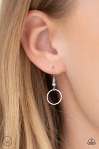 Silver circle hanging from a fish hook earring.