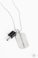 Pinched between a black leather fitting, a silver bullet pendant joins a silver dog tag at the bottom of a silver ball chain. The shimmery dog tag is stamped in the phrase, 