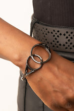 Load image into Gallery viewer, Encrusted in sections of glassy white rhinestones, two oversized gunmetal rings delicately overlap across the center of the wrist, resulting in a timeless bangle-like bracelet around the wrist. Features a hinged closure.  Sold as one individual bracelet.
