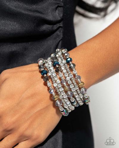 Threaded along a coiled wire, silver beads, white rhinestones in silver square fittings, and oil spill, blue, silver, and transparent faceted beads curl around the wrist, creating an eye-catching, infinity wrap-style bracelet around the wrist. Sold as one individual bracelet.