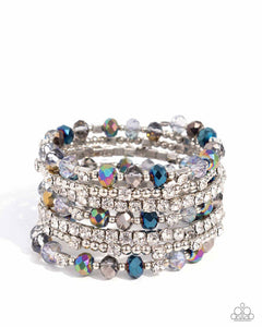 Threaded along a coiled wire, silver beads, white rhinestones in silver square fittings, and oil spill, blue, silver, and transparent faceted beads curl around the wrist, creating an eye-catching, infinity wrap-style bracelet around the wrist. Sold as one individual bracelet.