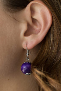 Purple wooden bead dangling from a silver fish hook earring.