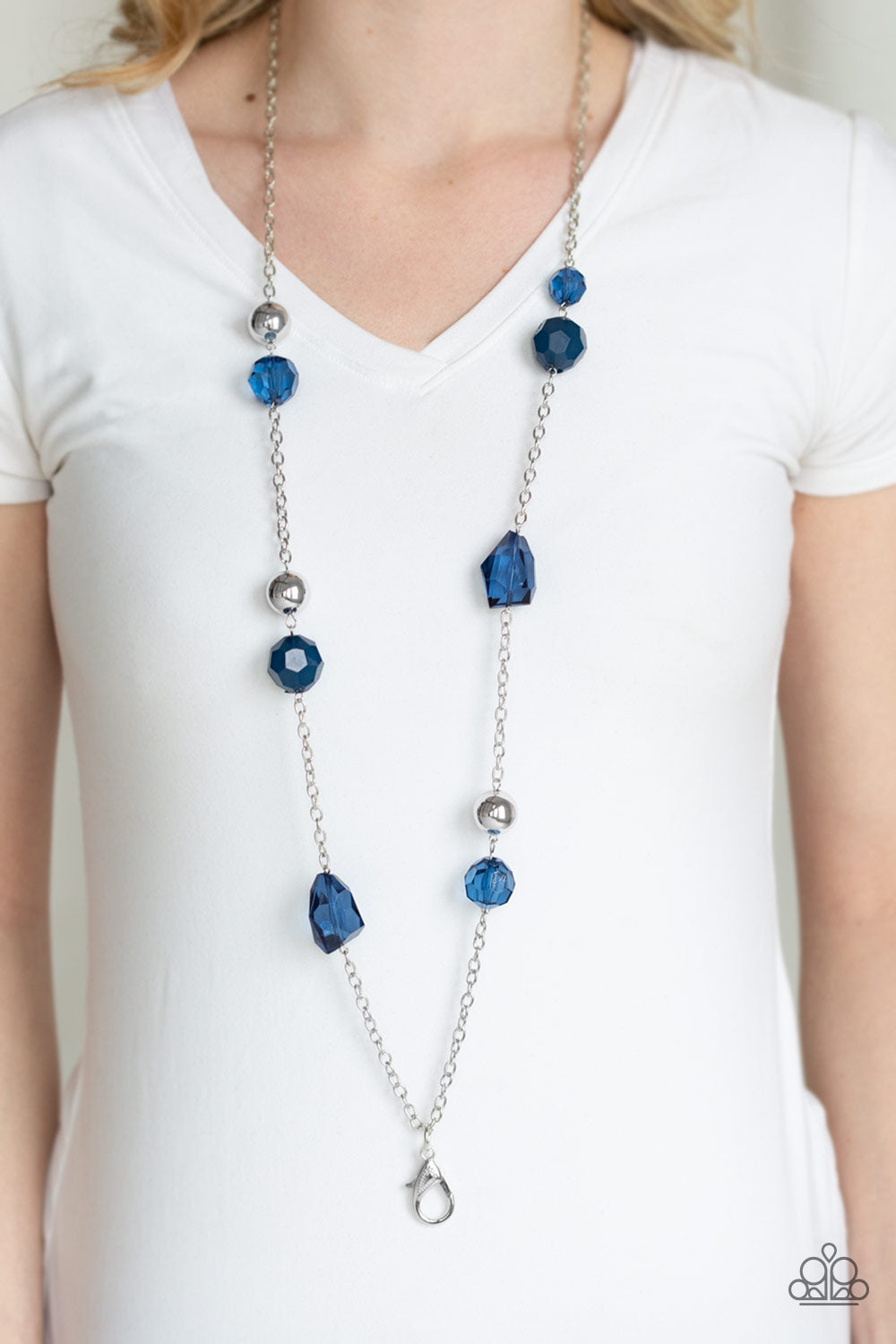 A collection of faceted blue gems, opaque blue beads, and polished silver beads trickle down a shimmery silver chain for a glamorous look. A lobster clasp hangs from the bottom of the design to allow a name badge or other item to be attached. Features an adjustable clasp closure.  Sold as one individual lanyard. Includes one pair of matching earrings.