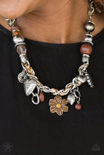 Load image into Gallery viewer, Brown and ivory cording is braided through a chunky silver chain. A unique variety of charms decorate the Blockbuster piece, including a delicate flower and a heart inscribed with the phrase &quot;With All My Heart&quot; on one side and a short bible verse on the other that reads, &quot;Love the Lord thy God with all your heart. Luke 10:27.&quot; Features an adjustable clasp closure. Sold as one individual necklace. Includes one pair of matching earrings.

