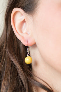 Yellow bead hanging from a silver fish hook earring.
