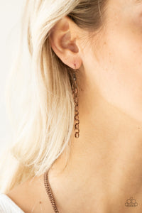 Copper chain hanging from a copper fish hook earring.