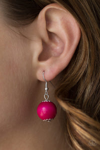 Pink wooden bead dangling from a silver fish hook earring.