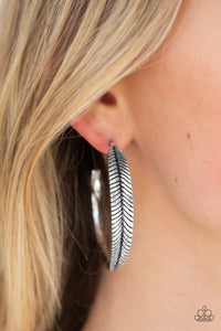 Featuring lifelike textures, a glistening silver feather hoop curls around the ear for a seasonal look. Earring attaches to a standard post fitting. Hoop measures 2" in diameter. Sold as one pair of hoop earrings.