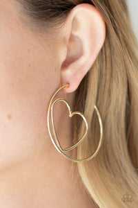 Shiny gold wire delicately bends into an airy heart frame inside a classic gold hoop, creating a flirtatious display. Earring attaches to a standard post fitting. Hoop measures approximately 2" in diameter. Sold as one pair of hoop earrings.