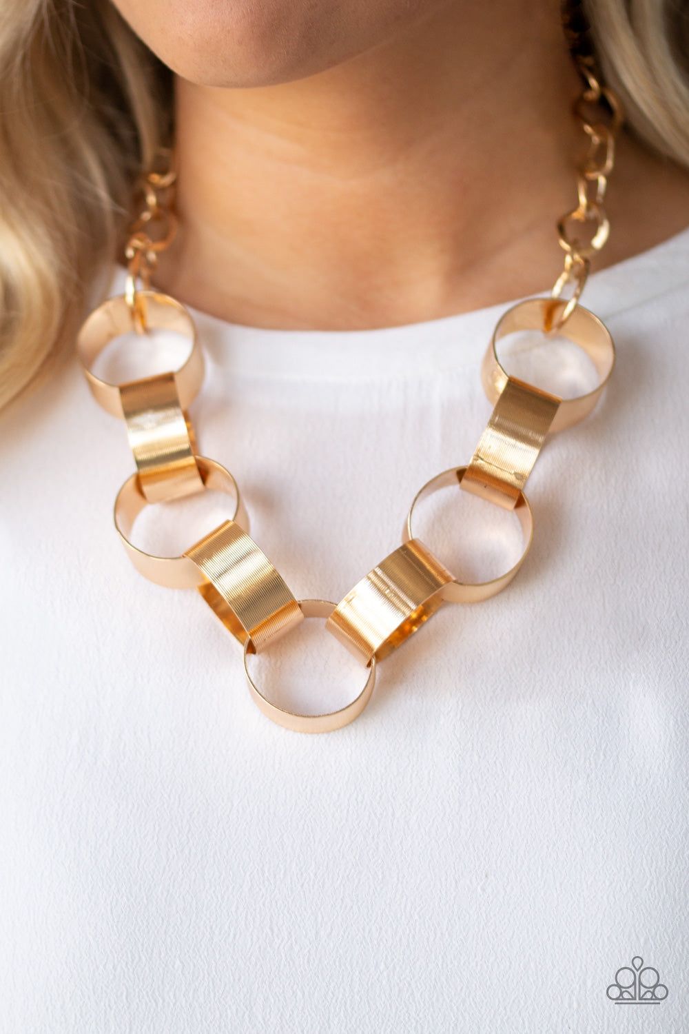 Etched in linear patterns, dramatically oversized gold links connect below the collar for a bold statement-making look. Features an adjustable clasp closure. Sold as one individual necklace. Includes one pair of matching earrings.