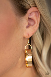 Gold circle hanging from a fish hook earring.