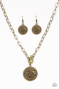 Embossed in a whimsical rosebud pattern, a shimmery brass frame swings below the collar for a casual look. Features a toggle closure. Sold as one individual necklace. Includes one pair of matching earrings.