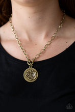 Load image into Gallery viewer, Embossed in a whimsical rosebud pattern, a shimmery brass frame swings below the collar for a casual look. Features a toggle closure. Sold as one individual necklace. Includes one pair of matching earrings.
