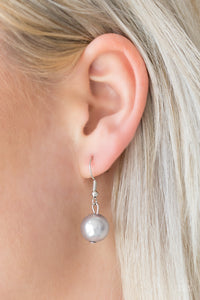 Silver pearl hanging from a silver fish hook earring.