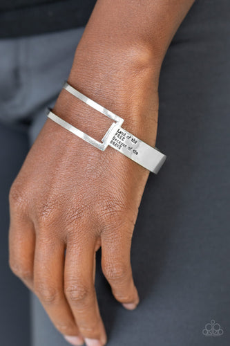 An airy rectangular frame attaches to a flat silver bar that curves around the wrist and is stamped in the phrase, “Land of the free because of the brave,” creating a patriotic inspired cuff. Sold as one individual.