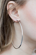 Load image into Gallery viewer, A skinny ribbon of silver curls into a bold hoop for a dramatic look. Earring attaches to a standard post fitting. Hoop measures 3” in diameter. Sold as one pair of hoop earrings.
