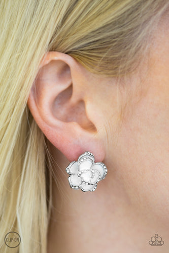 The silver edges of a white rosebud are encrusted in glittery white rhinestones for a whimsical look. Earring attaches to a standard clip-on fitting.  Sold as one pair of clip-on earrings.