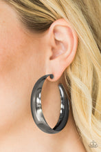 Load image into Gallery viewer, A thick ribbon of glistening gunmetal curls into a dramatic hoop for a bold industrial look. Earring attaches to a standard post fitting. Hoop measures 2 1/2” in diameter.  Sold as one pair of hoop earrings.
