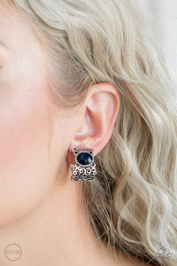 Brushed in an antiqued shimmer, vine-like filigree climbs into a glistening silver hoop. A glittery blue rhinestone is pressed into the top of the frame for a regal finish. Earring attaches to a standard clip-on fitting.  Sold as one pair of clip-on earrings.