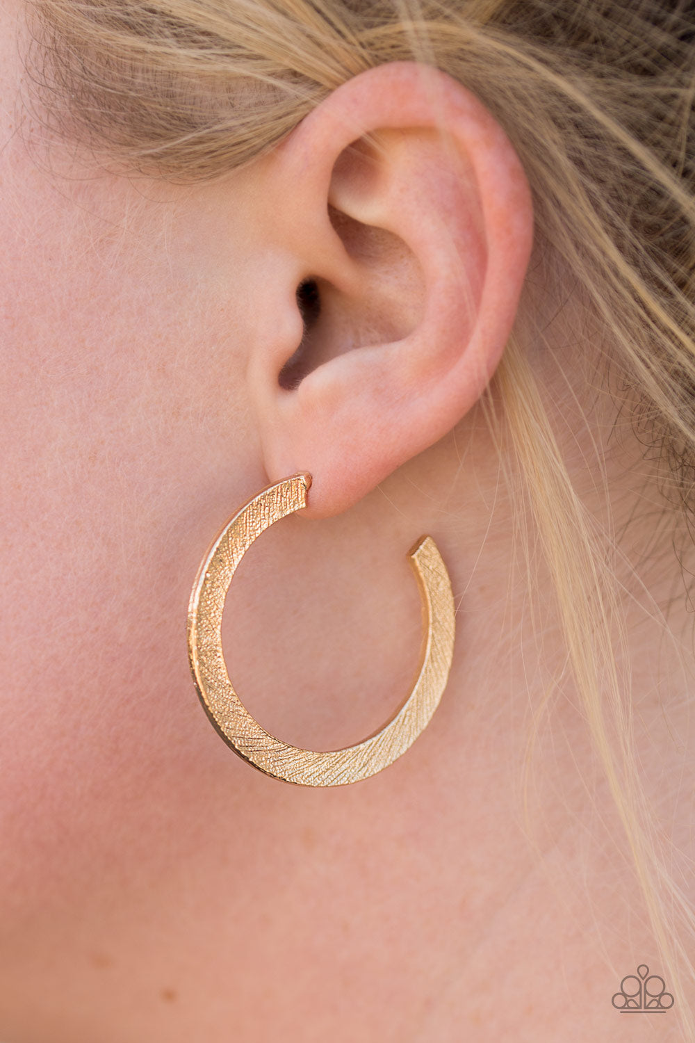 Etched in a scratched shimmer, a flat gold bar curls around the ear, creating a blinding sparkle. Earring attaches to a standard post fitting. Hoop measures 1 1/2” in diameter.  Sold as one pair of hoop earrings.