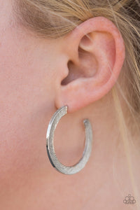 Etched in a scratched shimmer, a flat silver bar curls around the ear, creating a blinding sparkle. Earring attaches to a standard post fitting. Hoop measures 1 1/2” in diameter.  Sold as one pair of hoop earrings.