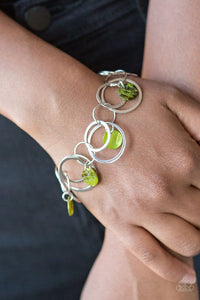 Bits of iridescent green shell swing from the bottoms of mismatched silver hoops around the wrist for a summery look. Features an adjustable clasp closure.