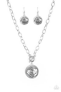 Embossed in a whimsical rosebud pattern, a shimmery silver frame swings below the collar for a casual look. Features a toggle closure. Sold as one individual necklace. Includes one pair of matching earrings.