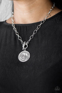 Embossed in a whimsical rosebud pattern, a shimmery silver frame swings below the collar for a casual look. Features a toggle closure. Sold as one individual necklace. Includes one pair of matching earrings.