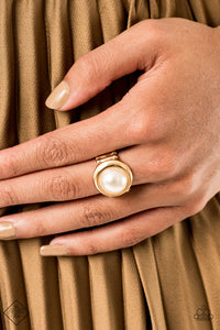 A glistening gold frame asymmetrically encircles a pearly white beaded centerpiece, adding a timeless twist to the classically offset display. Features a stretchy band for a flexible fit. Individual ring.