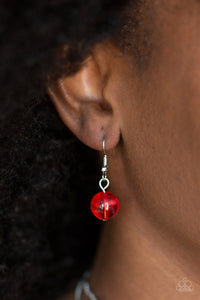 Single red bead hanging from a fish hook earring.