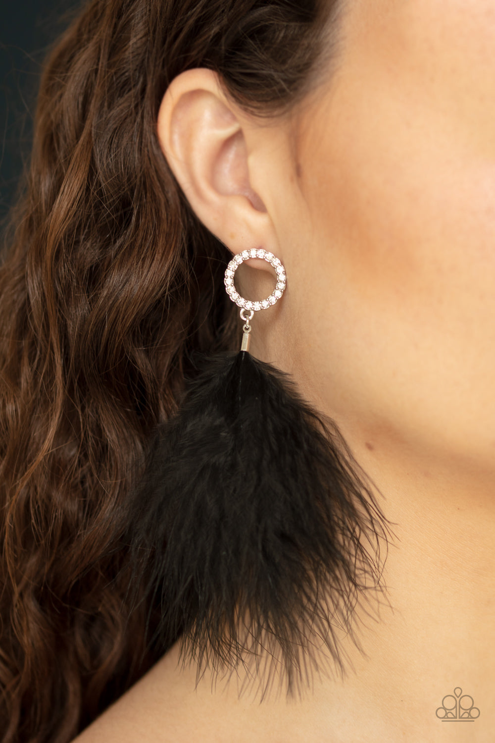 A fuzzy black feather swings from the bottom of a white rhinestone encrusted silver ring, creating a refined lure. Earring attaches to a standard post fitting. Sold as one pair of post earrings.